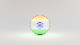 A 3D sphere with the Indian flag design, featuring horizontal stripes of saffron, white with a blue Ashoka Chakra at the center, and green. The sphere is set against a light, neutral background.