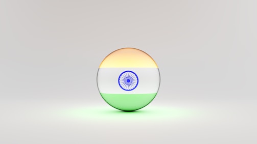 A 3D sphere with the Indian flag design, featuring horizontal stripes of saffron, white with a blue Ashoka Chakra at the center, and green. The sphere is set against a light, neutral background.