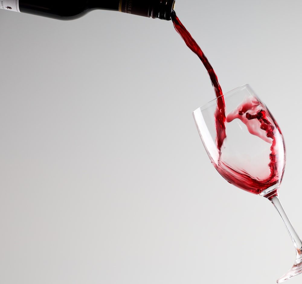 a glass of red wine being poured into it