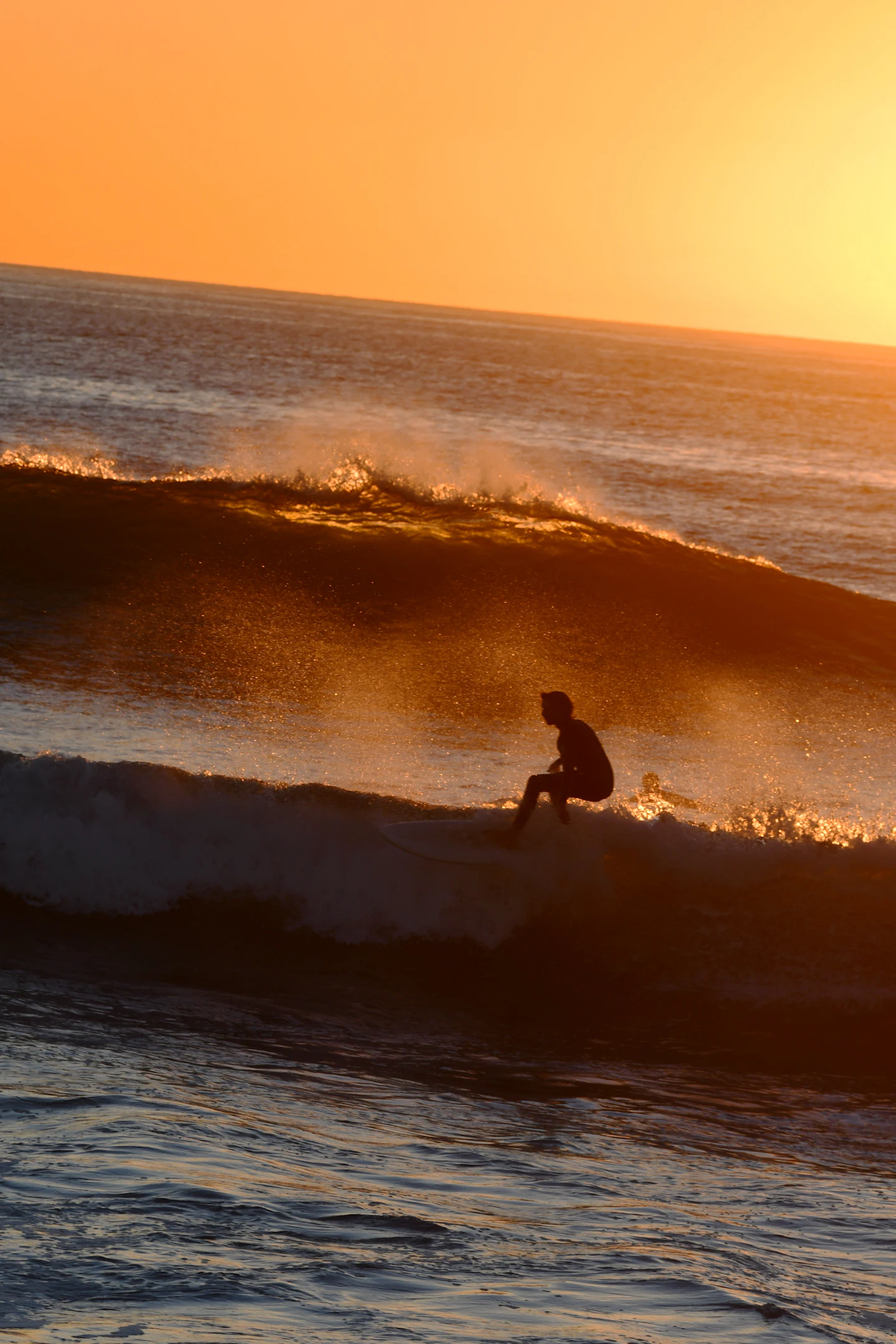 A surfer on a wave at sunset