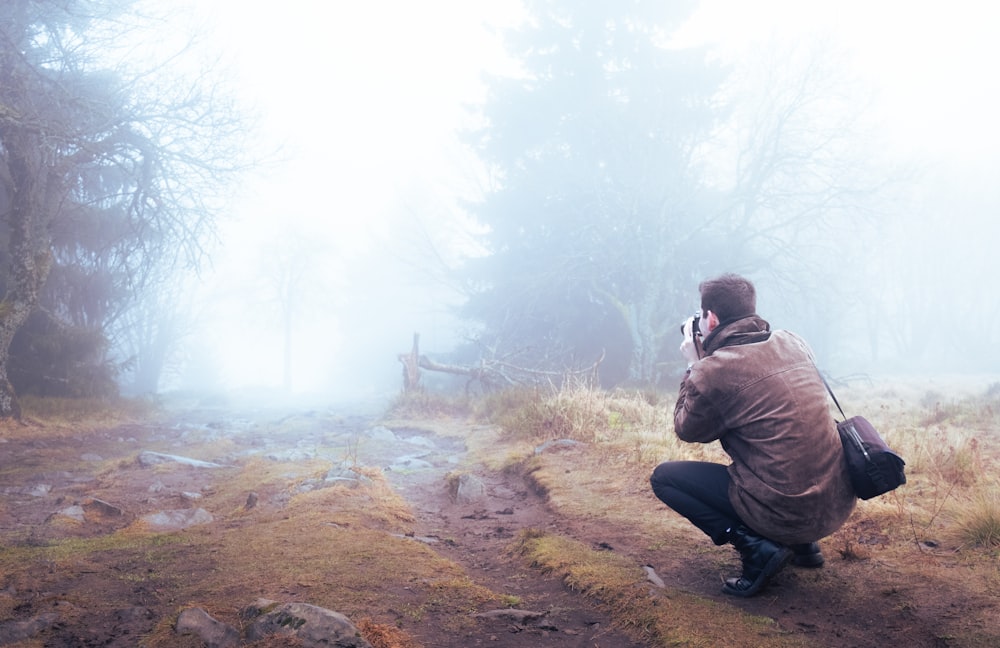 a man taking a picture of a foggy forest