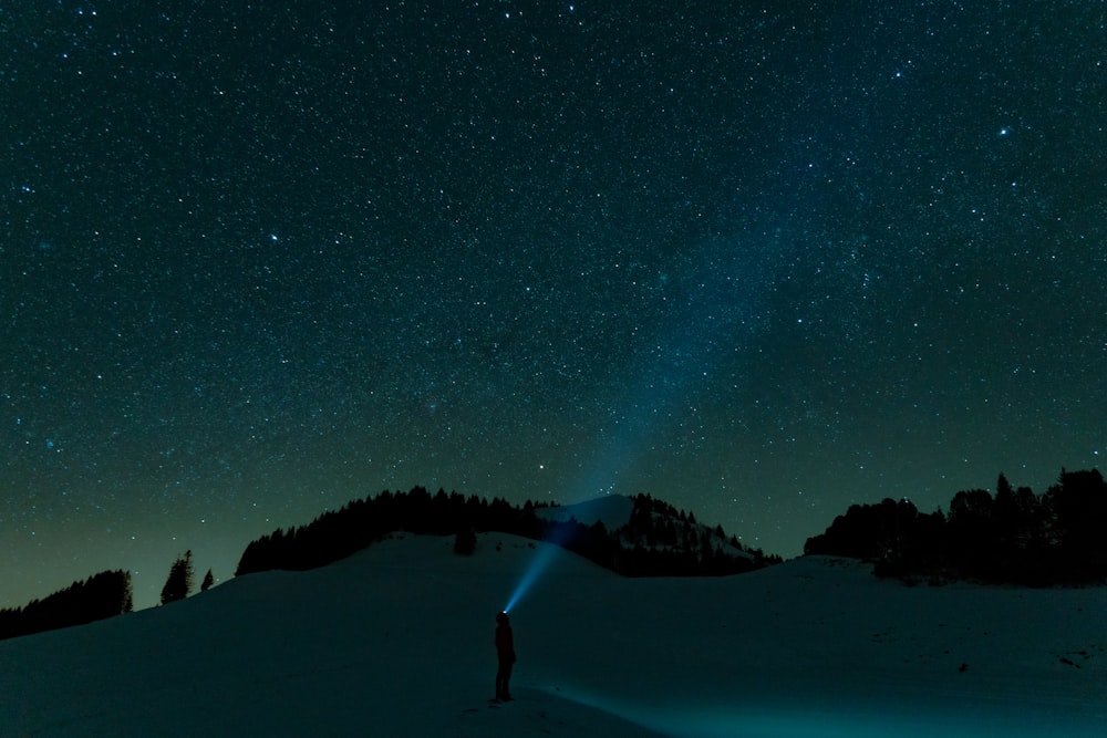 Una persona in piedi nella neve sotto un cielo notturno