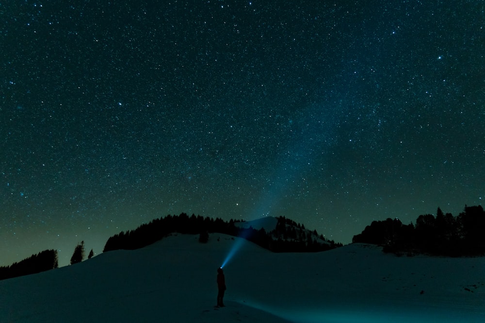 a person standing in the snow under a night sky