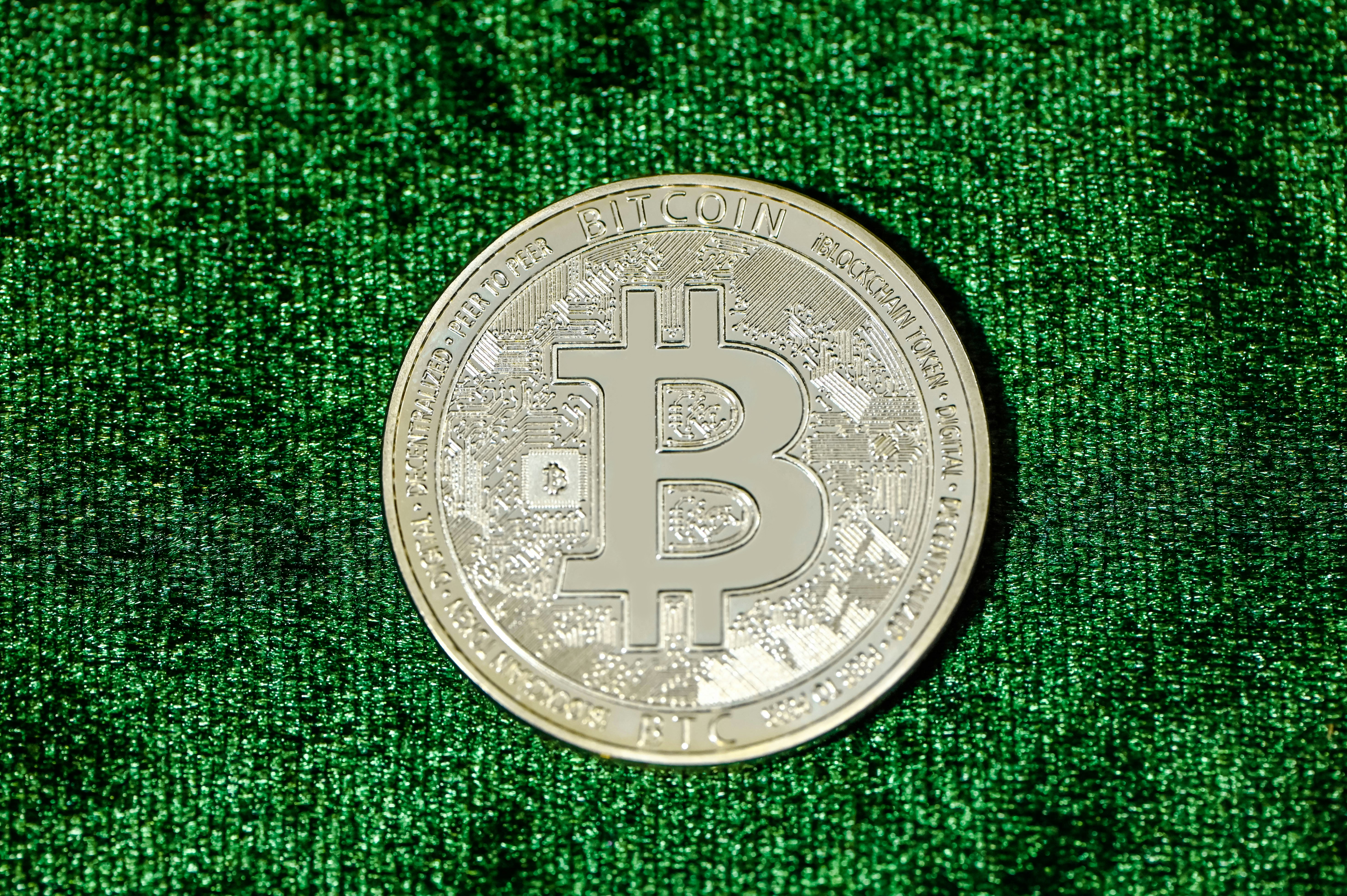 A Bitcoin laying on a green background