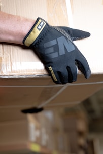 a person's hand wearing a black glove on top of a box