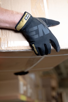 a person's hand wearing a black glove on top of a box