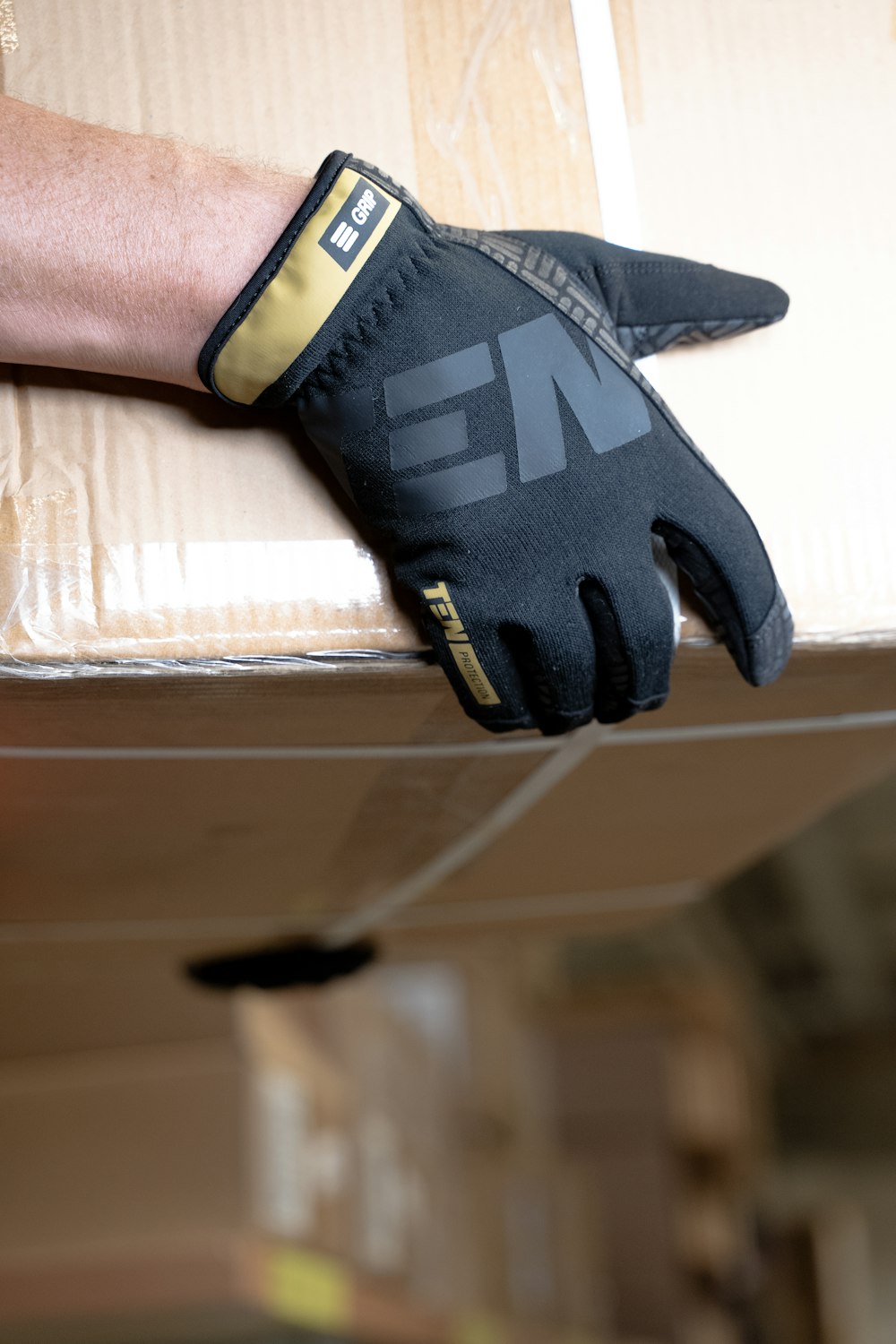 a person's hand wearing a black glove on top of a box