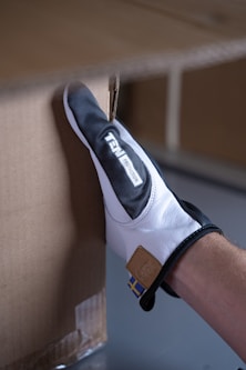 a person wearing a white and black glove is putting something in a box