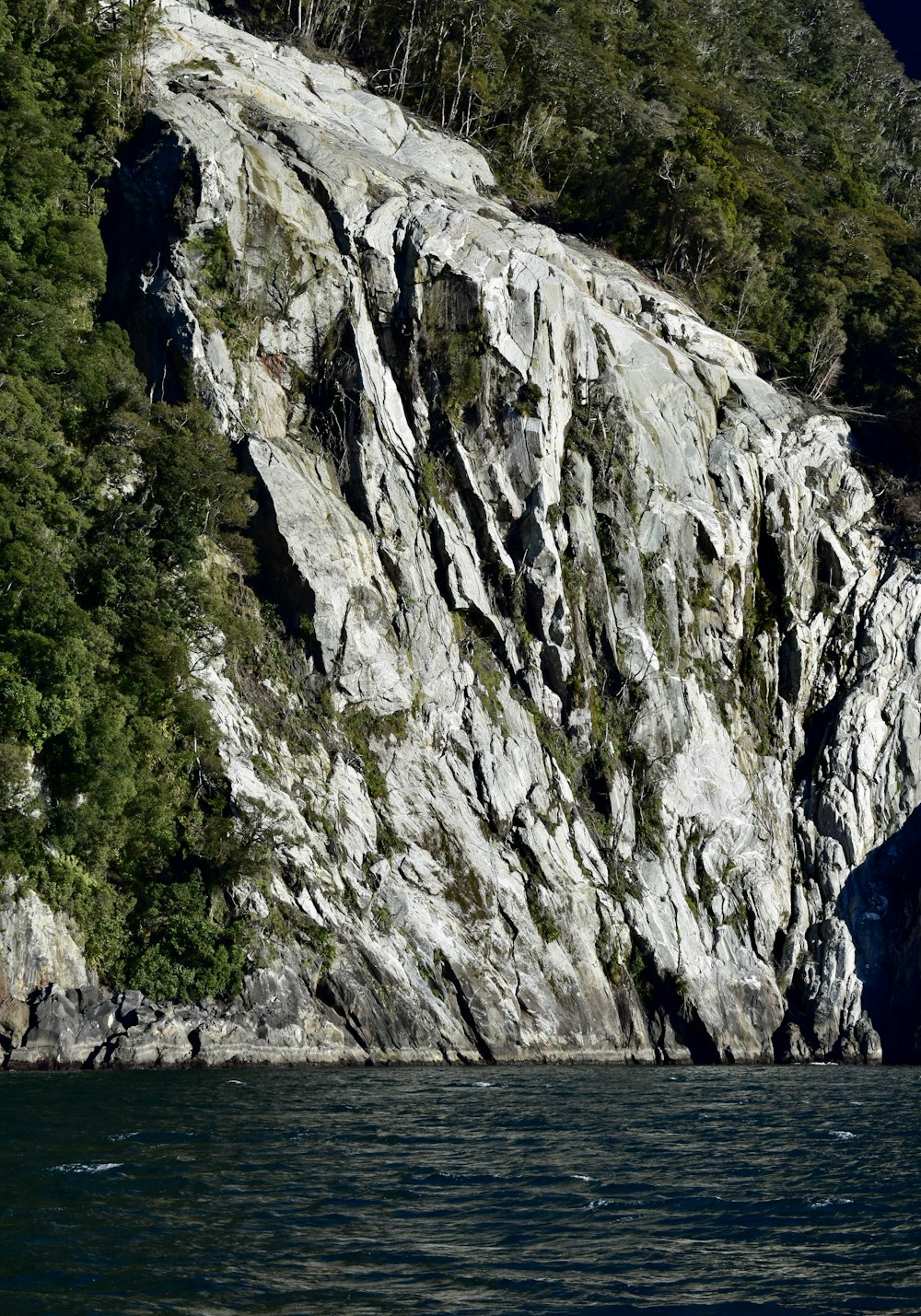 a large rock face next to a body of water