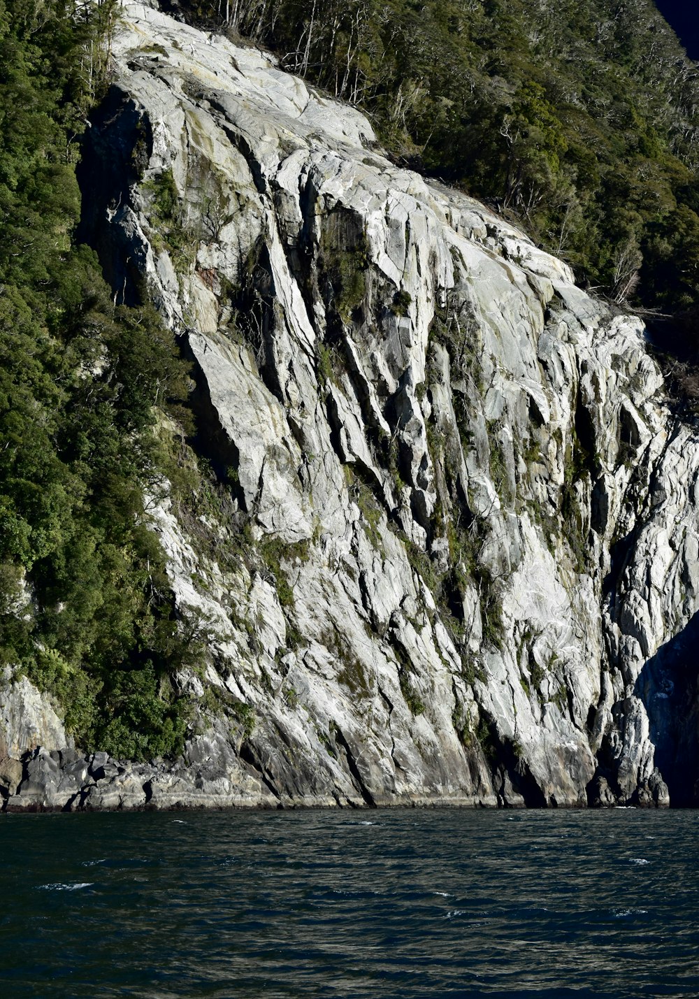 una gran pared rocosa junto a un cuerpo de agua