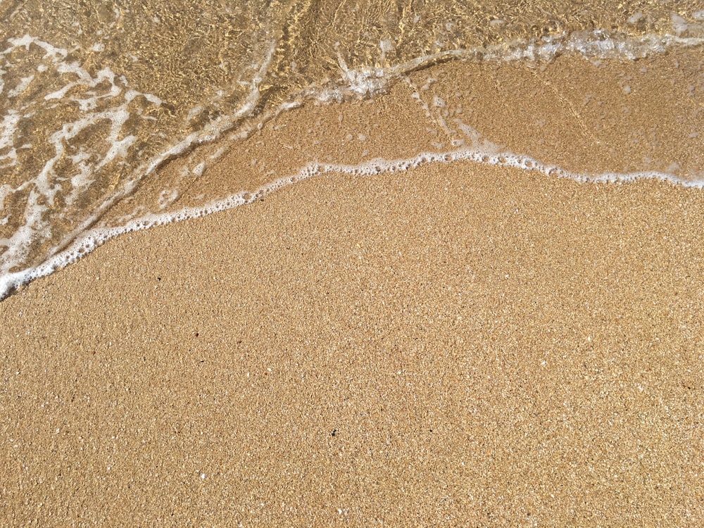 a sandy beach with a wave coming in to shore