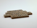 Wooden tiles with letters arranged to spell 'BUT WHAT ABOUT YOU', resembling Scrabble pieces. The background is a smooth gradient of white to light gray, creating a soft and minimalist look.