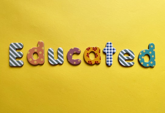 Various letters spelling out the word 'Educated' on a yellow background. Each letter is uniquely designed with different patterns and colors.