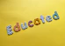 Colorful letters spelling the word 'Educated' are arranged on a bright yellow background. Each letter features a different pattern, such as stripes, polka dots, flowers, and stars.