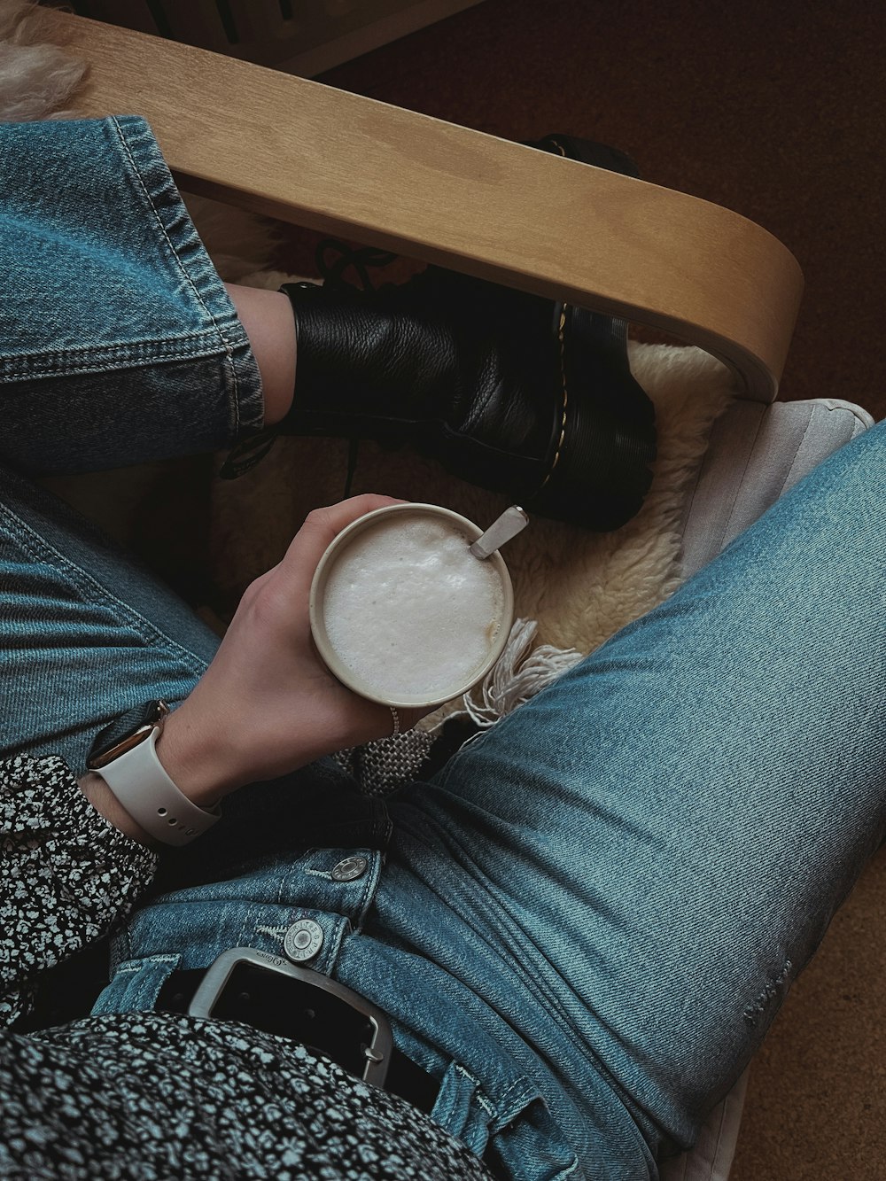 a person holding a cup of coffee in their lap