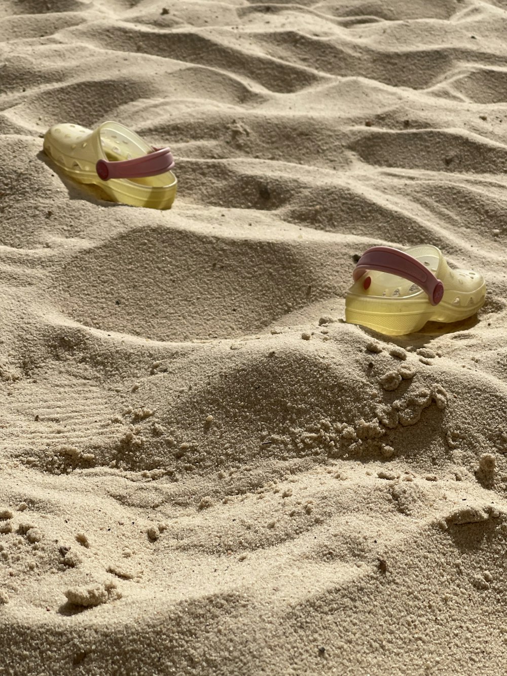 a pair of shoes sitting on top of a sandy beach