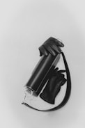 A sleek, cylindrical leather handbag is paired with matching black leather gloves. The bag features a silver clasp and a strap, adding a touch of elegance.