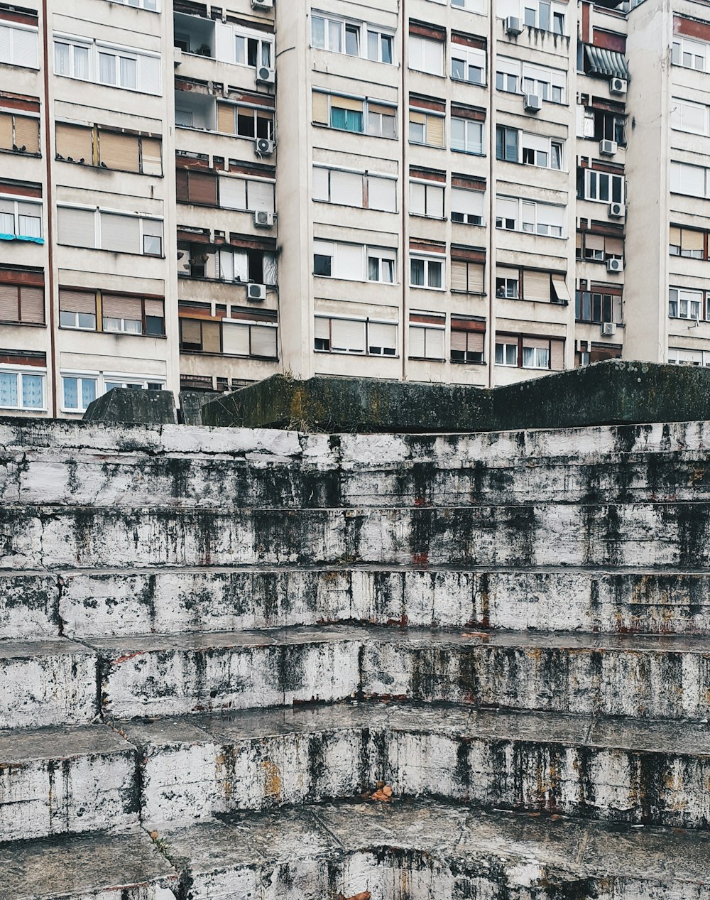 a person sitting on a ledge in front of a building