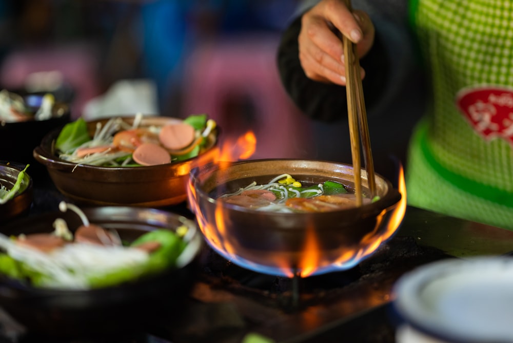 a person stirring a bowl of soup with chopsticks