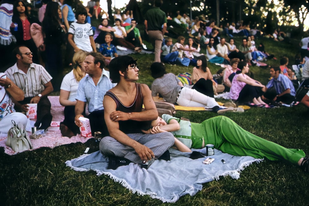 a group of people sitting on top of a lush green field