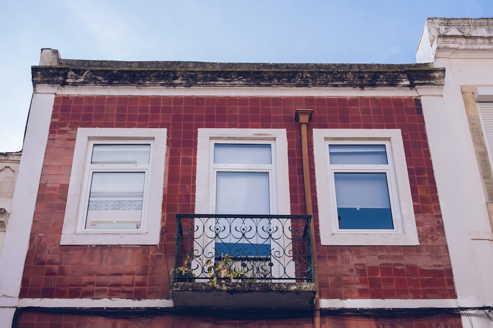 a red brick building with two windows and a balcony