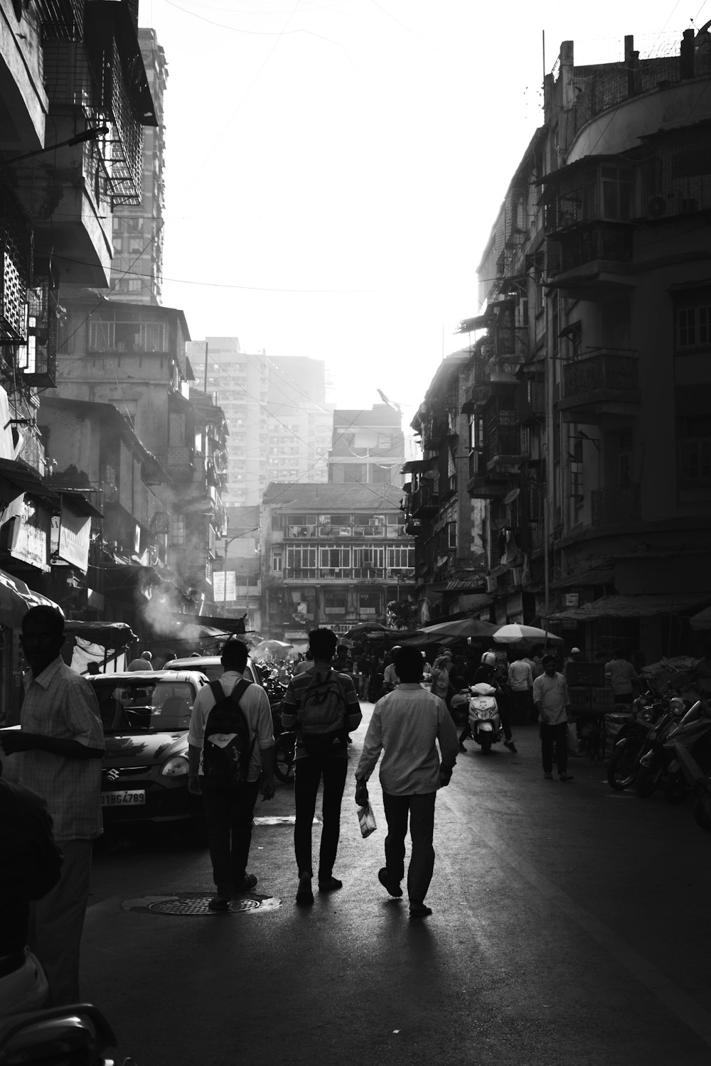 a group of people walking down a street next to tall buildings