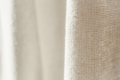 Close-up of textured fabrics in gentle beige and cream hues, highlighting the quality and detail of the collection.