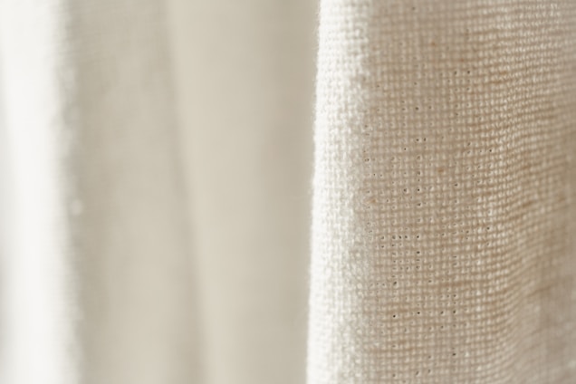 Close-up of finely woven fabric with subtle ochre red and toasted beige tones reflecting premium textile craftsmanship.