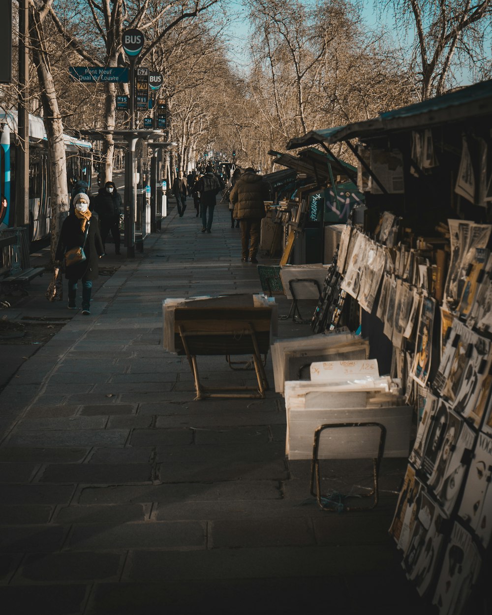 people walking down a sidewalk next to a sidewalk market