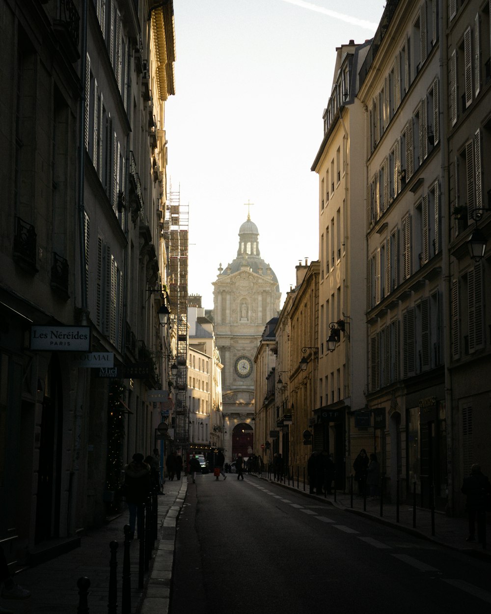 a city street lined with tall buildings and a clock tower