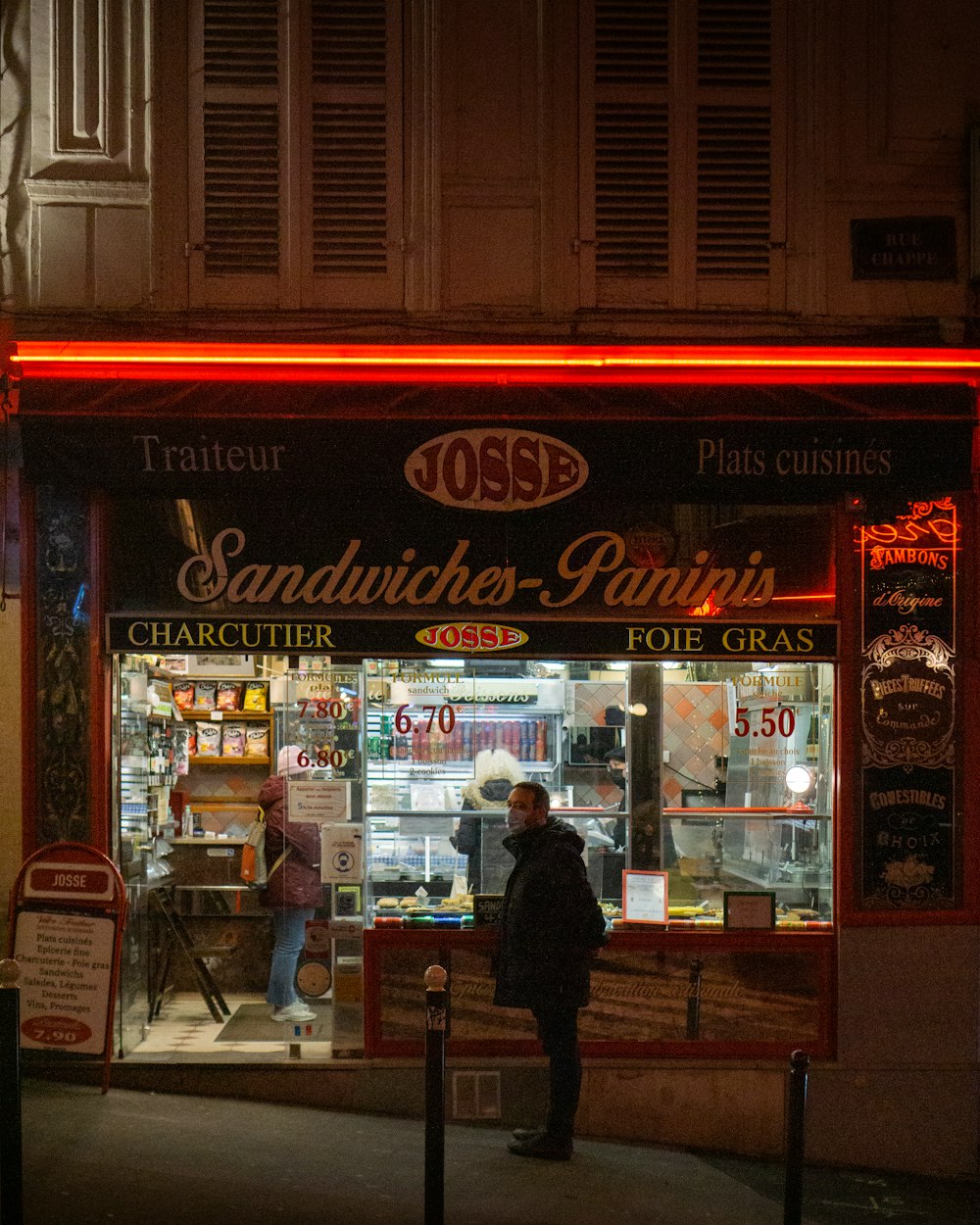 a person standing outside of a store at night