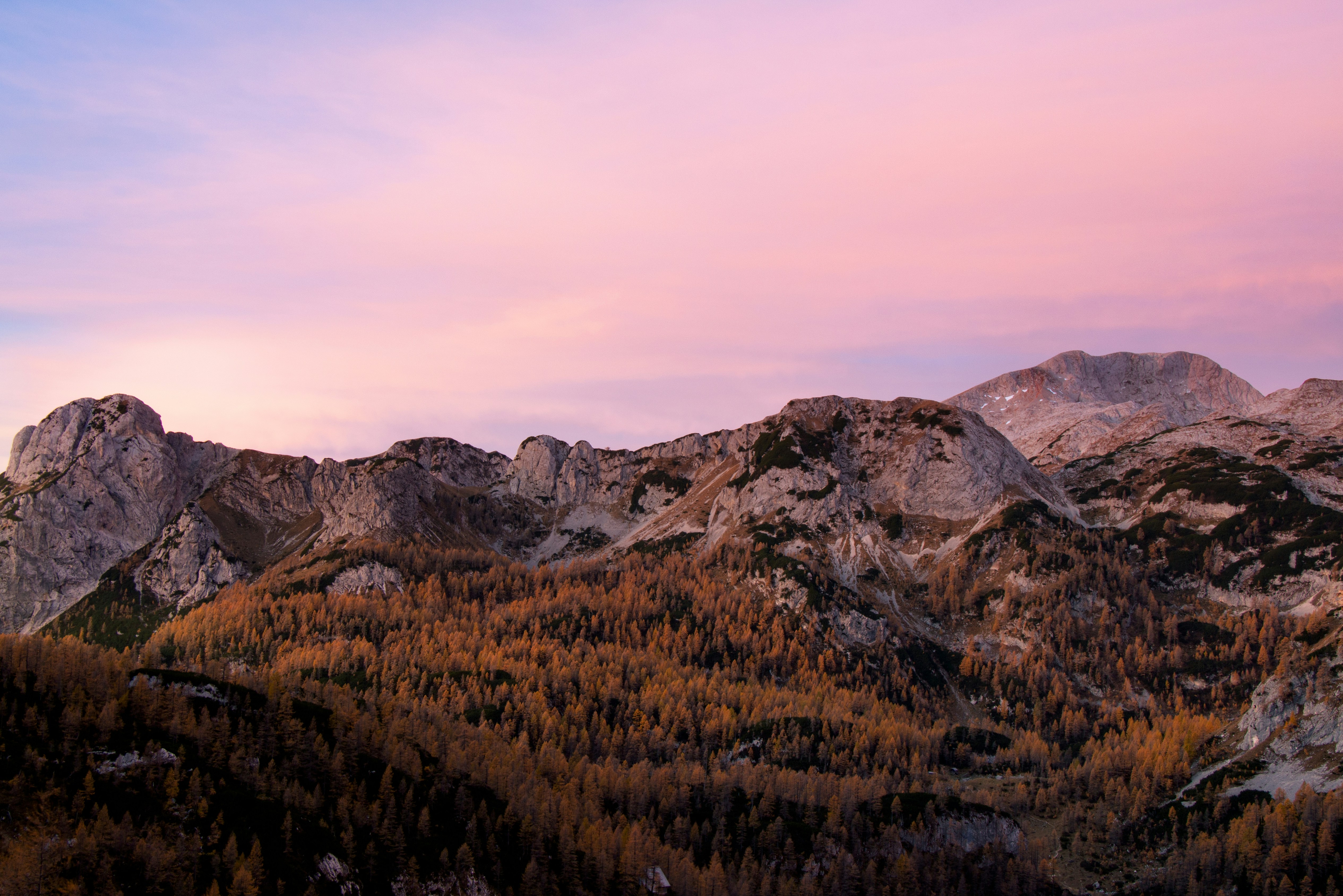 a mountain range with a pink sky in the background, Beautiful pink sunrise sky I experienced on my hike through the Julian Alps in Slovenia. 