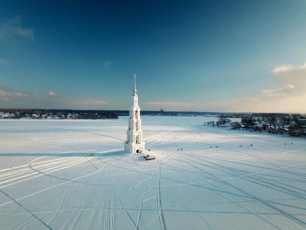 a tall white tower sitting in the middle of a snow covered field