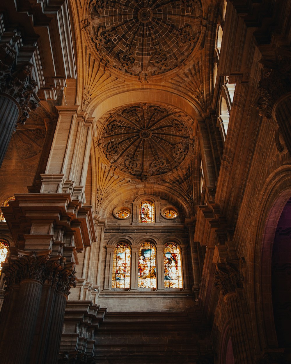 the ceiling of a large cathedral with stained glass windows