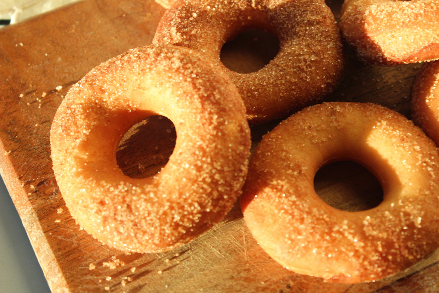 Round donuts coated in cinnamon sugar, piled close together