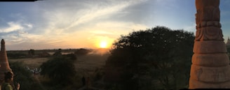 Panoramic shot capturing the vast Cerrado landscape around the three stones at sunset.