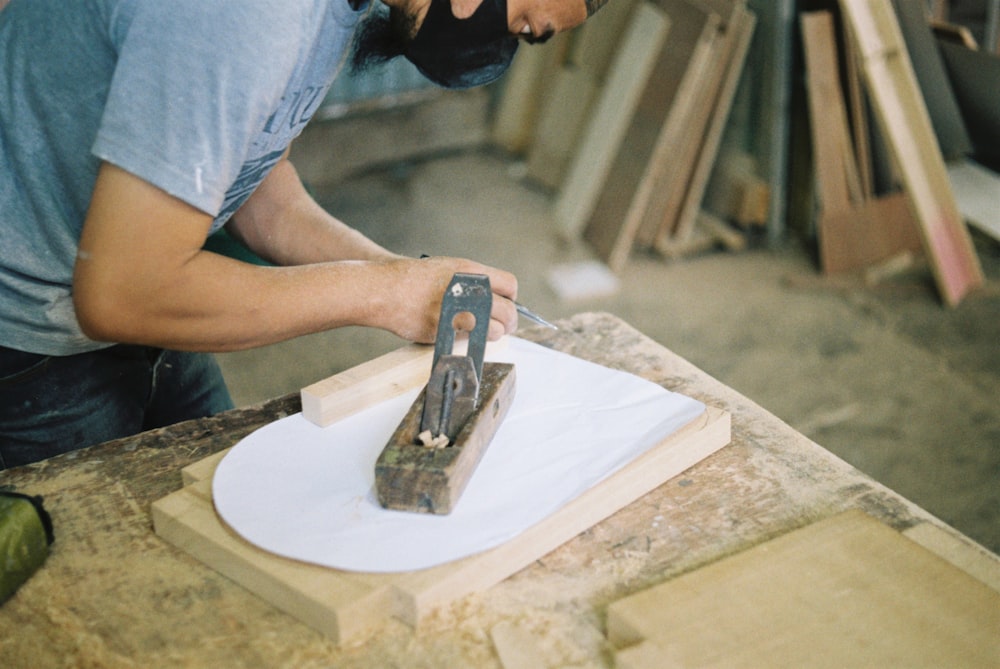 a man cutting a piece of wood with a pair of scissors