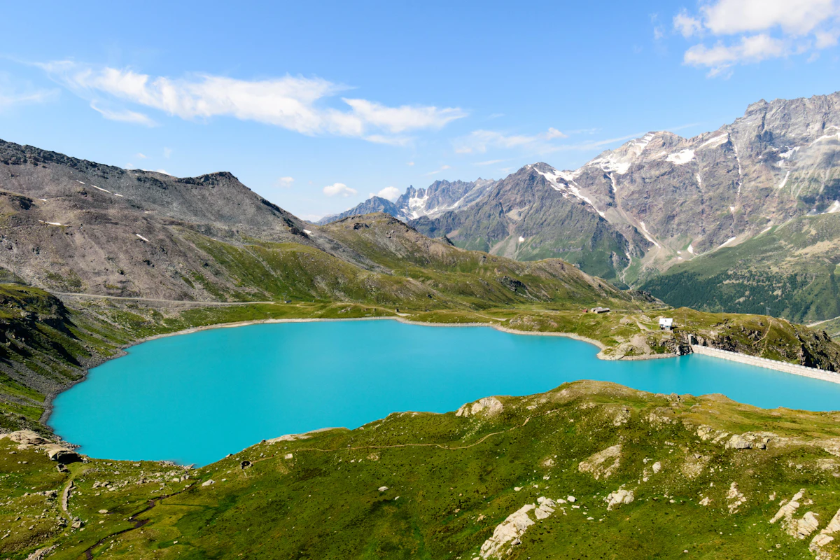 A turquoise lake in a bowl of rock and grass above Breuil-Cervinia