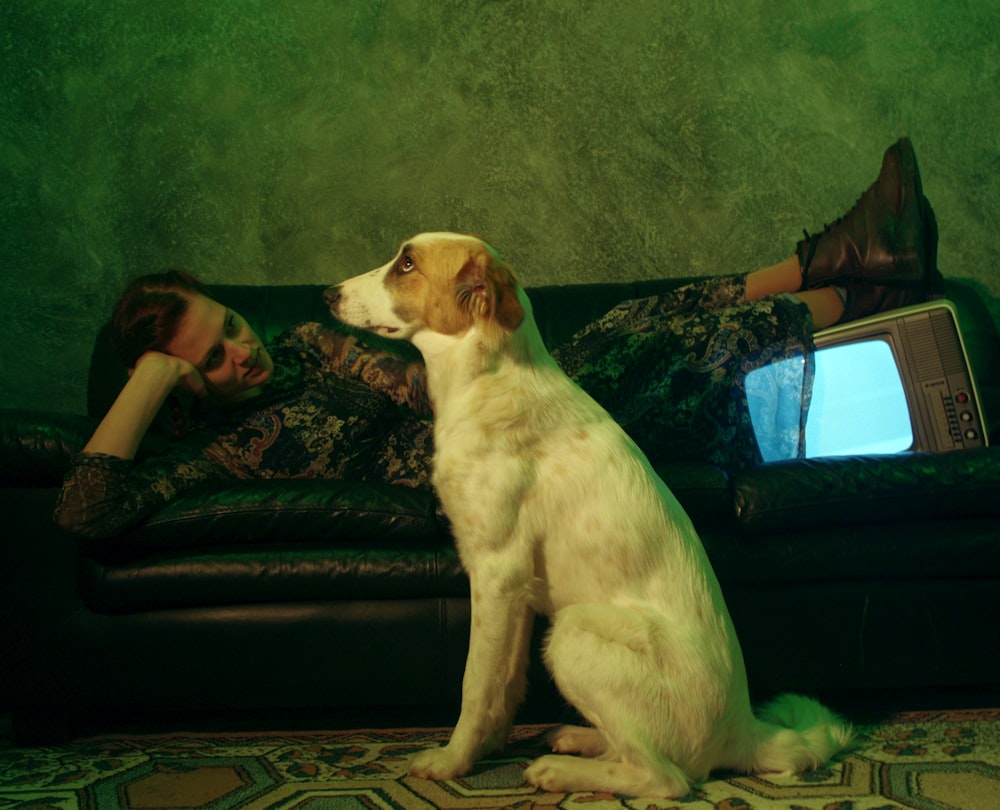 a woman laying on a couch next to a dog