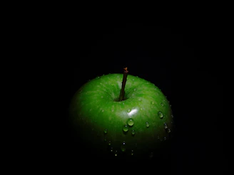A vibrant green apple with dew drops on a clean white background symbolizing freshness and eco-consciousness.