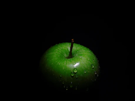 A vibrant green apple with dew drops on a clean white background symbolizing freshness and eco-consciousness.