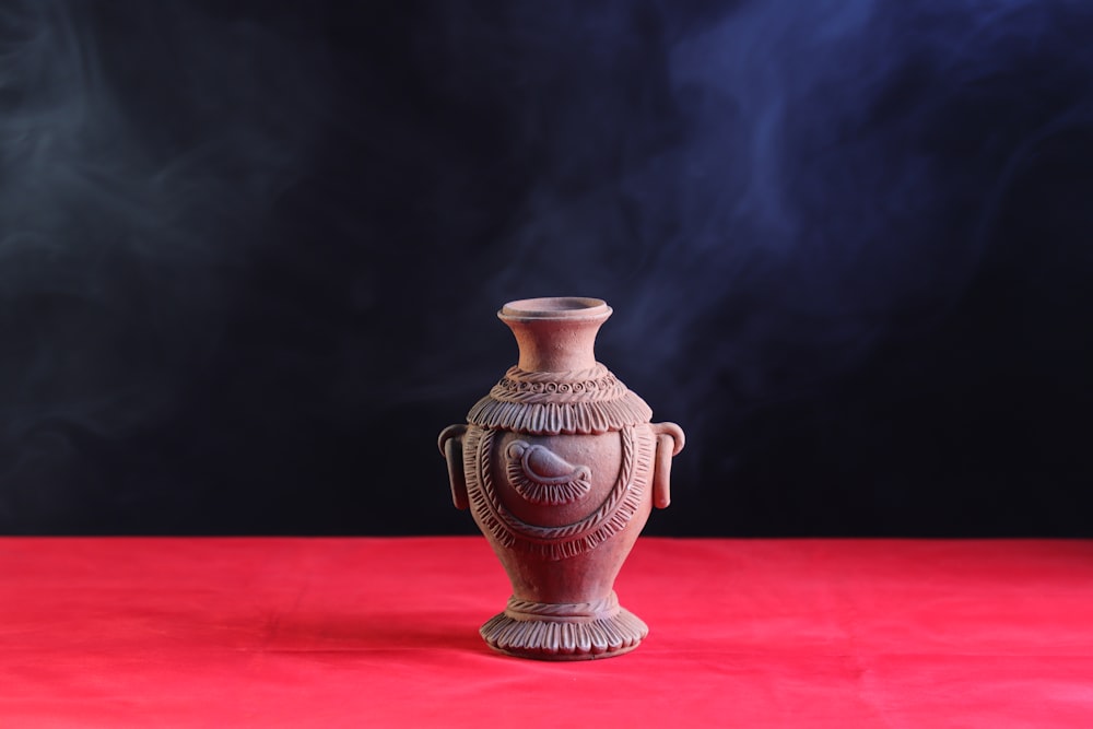 a brown vase sitting on top of a red table