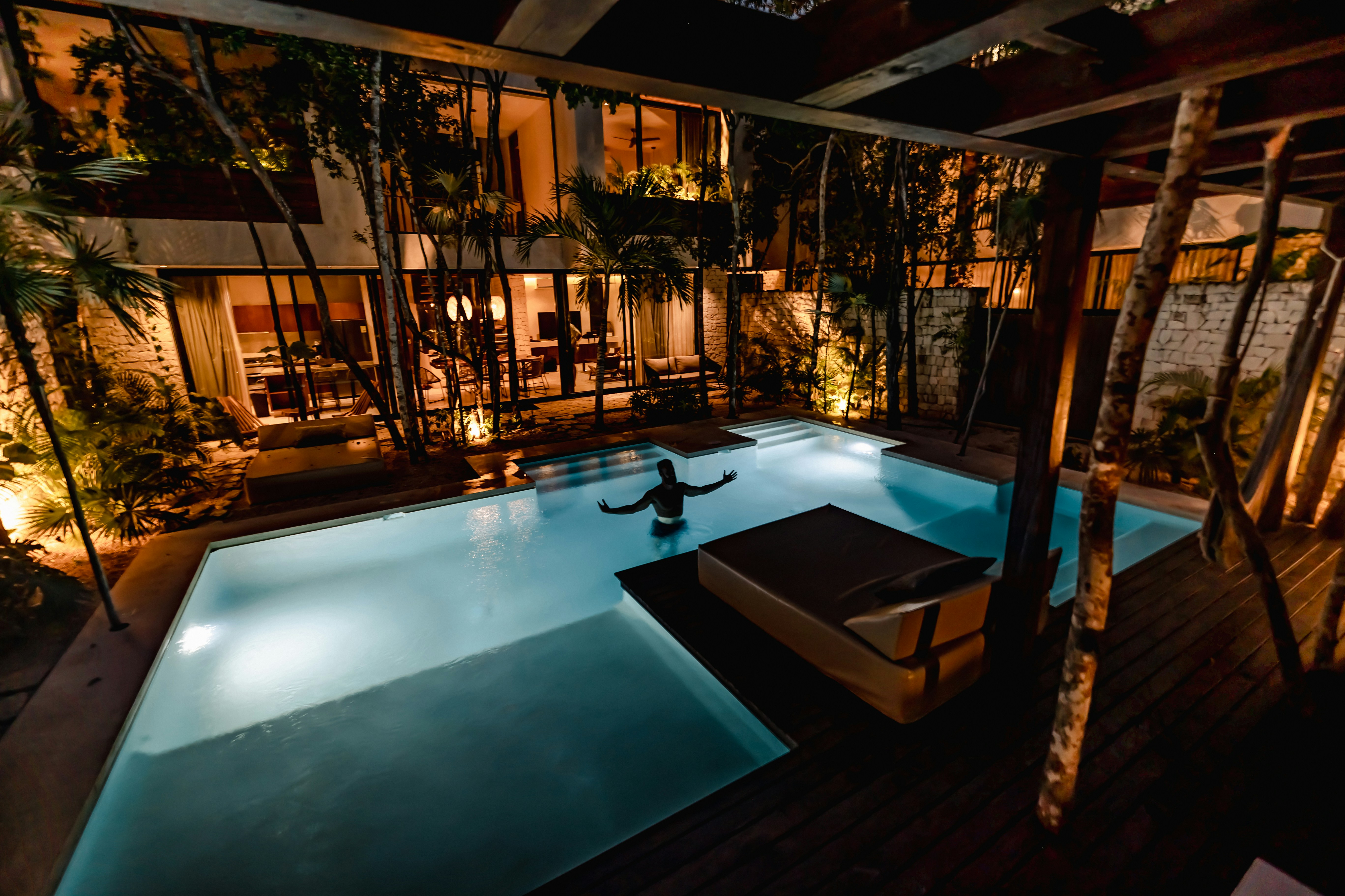 a large swimming pool surrounded by trees at night