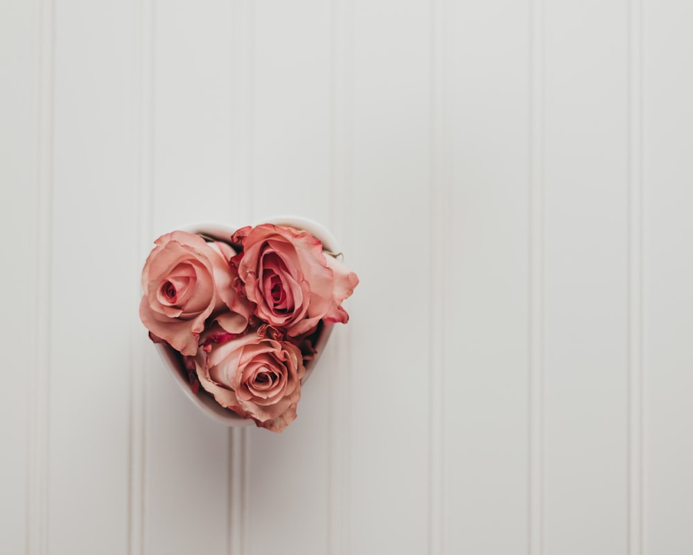 a bunch of pink roses in a white vase