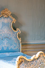 Elegant temple-inspired pet bed in deep navy with gold accents, set against a soft cream background.