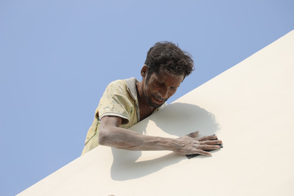 a man leaning against a wall with his hand on a cell phone