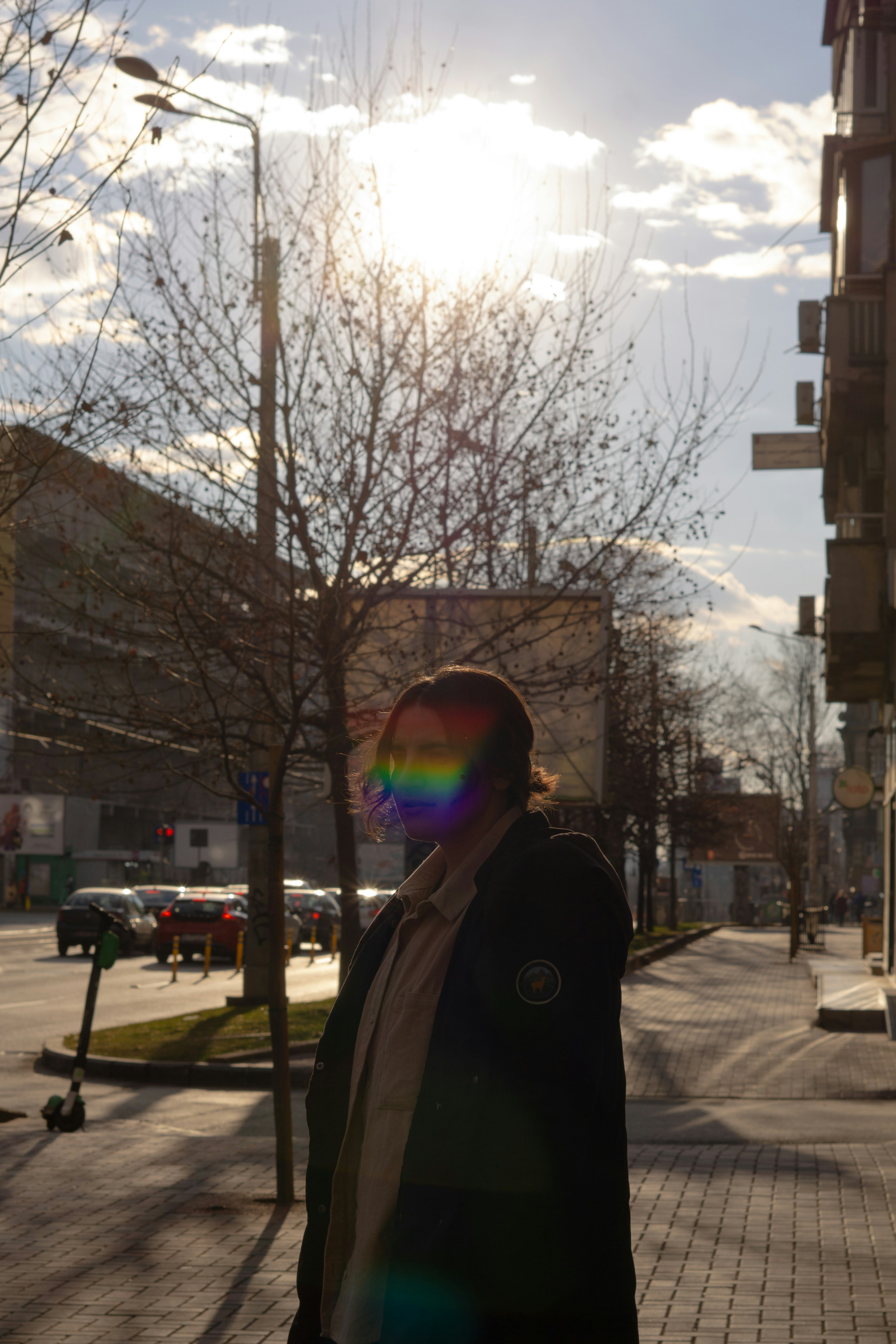 a man standing on a sidewalk next to a tree