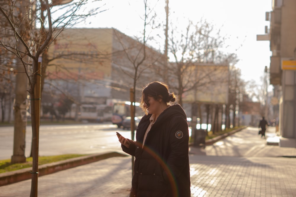 a woman standing on a sidewalk using a cell phone
