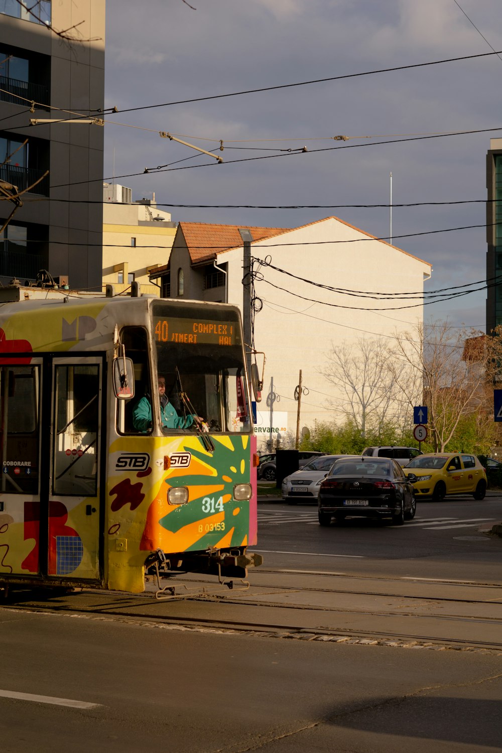 a colorful bus driving down a street next to tall buildings