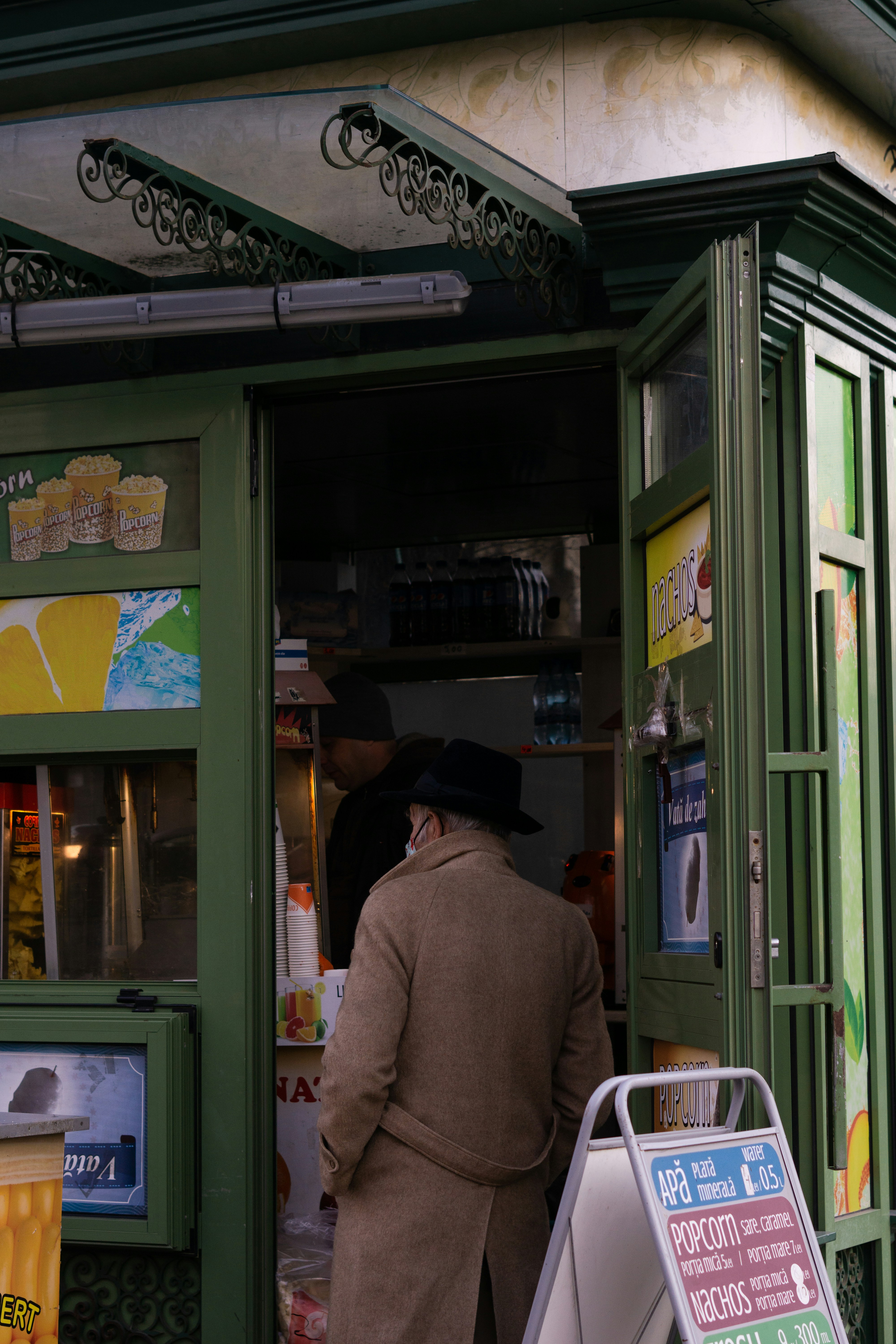 a man standing outside of a green store